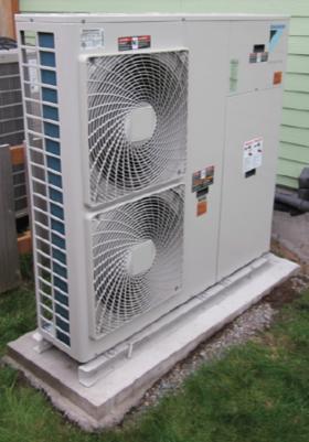 An example of a air-to-water heat pump on a concrete base out side a house, along with symbols used to represent it.