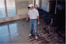 A person installing gypsum on top of the manifold tubing.